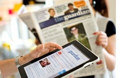 Tablet mit digitaler Zeitung neben gedruckter Zeitung und lesender Person